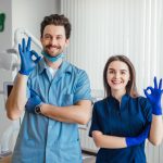 foto-dentista-sonriente-pie-brazos-cruzados-su-colega-mostrando-signo-bien.jpg
